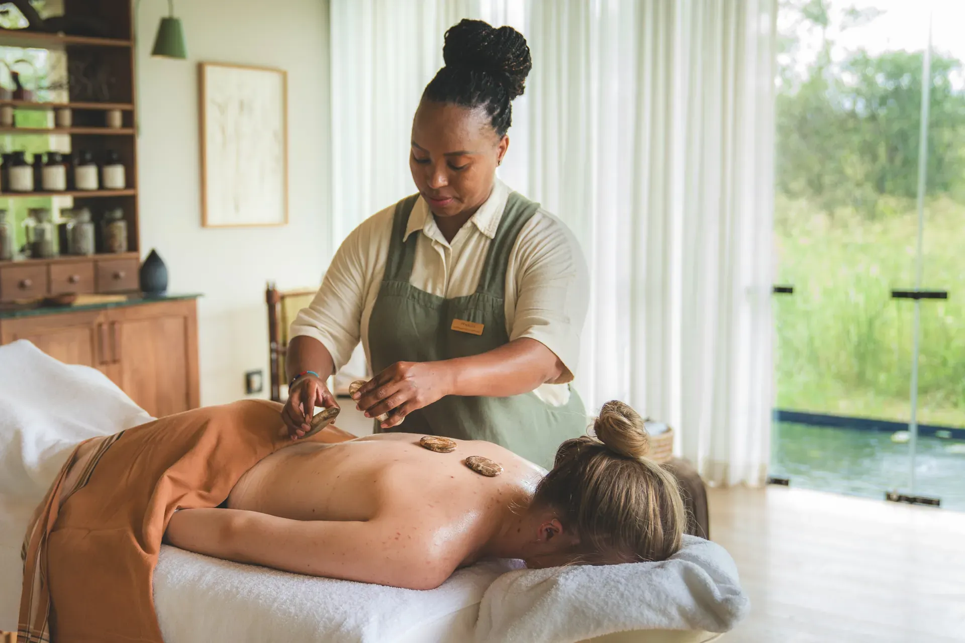 Woman receiving a hot stone massage on a treatment bed at Monwana spa.