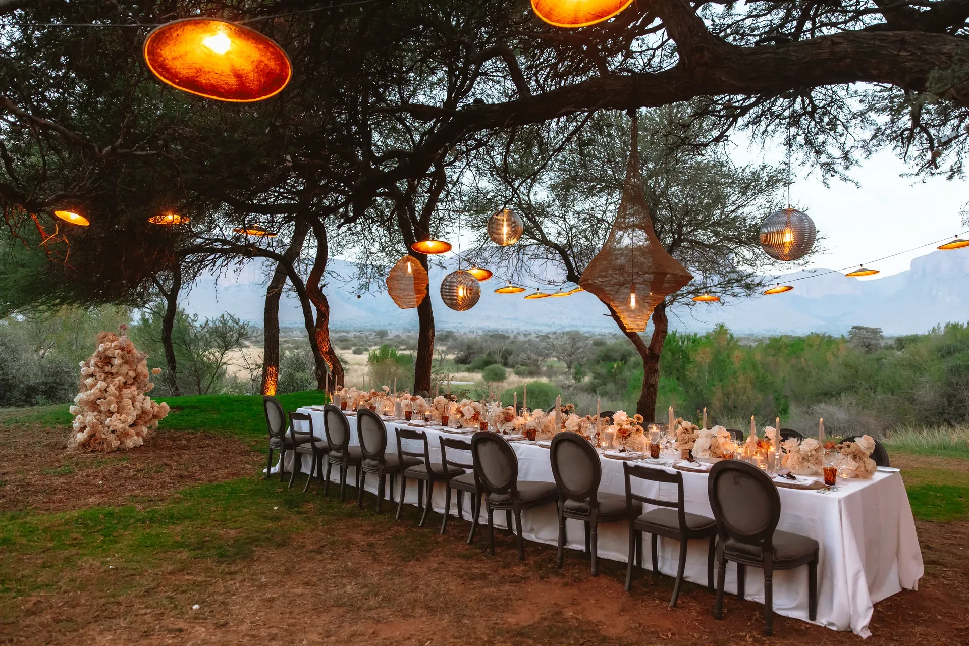 Sunset wedding ceremony at Marataba with hanging lights, bush, and mountain views.