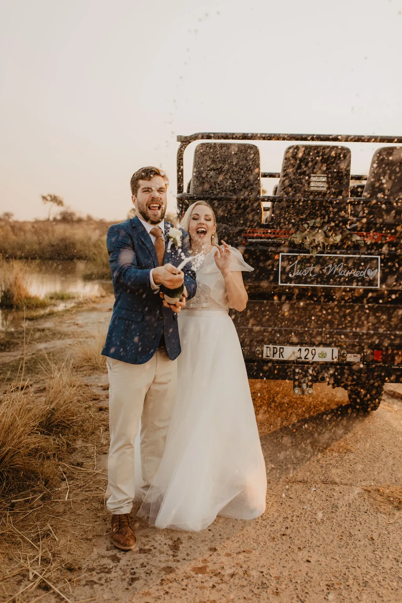 Just-married guests popping champagne with a game drive vehicle in the background at Marataba.