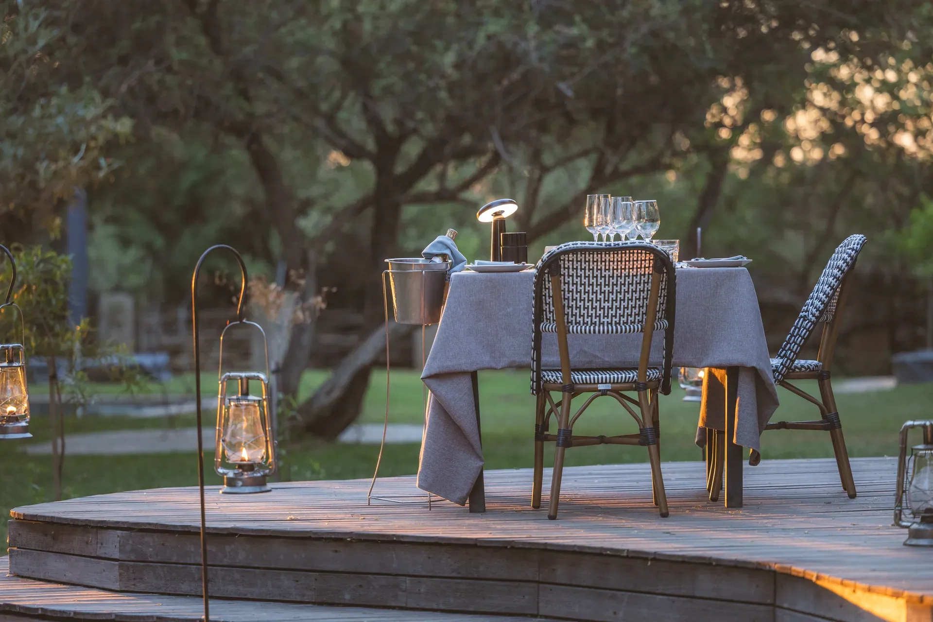 Romantic dinner setup outdoors at MTSL with a table and chairs on a wooden deck amid nature