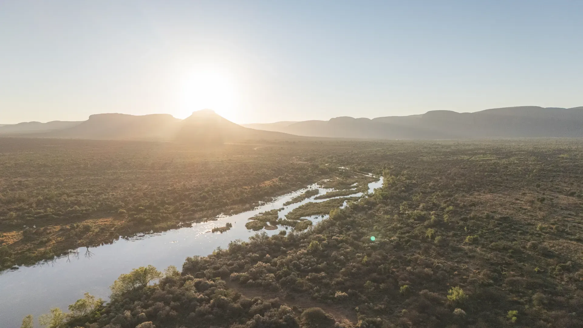 Aerial view of a rugged coastline with cliffs and the ocean at sunrise