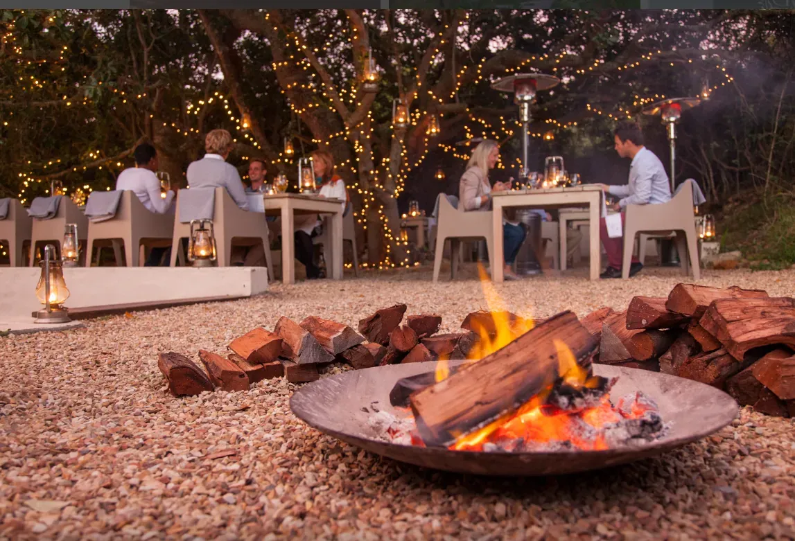 Outdoor milestone celebration setup with a fire pit, festive lighting and decorated seating area